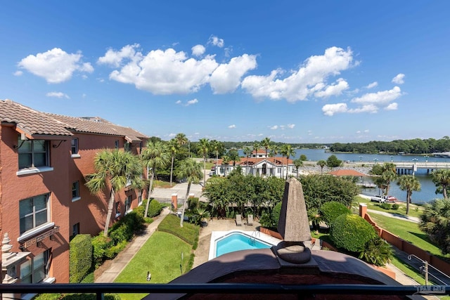 view of pool with a water view and a lawn