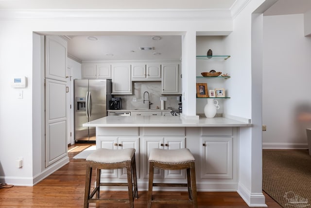 kitchen featuring kitchen peninsula, a kitchen breakfast bar, hardwood / wood-style floors, and stainless steel fridge with ice dispenser