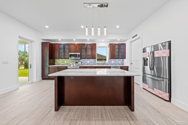 kitchen featuring plenty of natural light, a kitchen island, hanging light fixtures, and appliances with stainless steel finishes