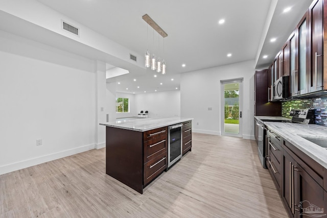 kitchen with a center island, hanging light fixtures, beverage cooler, stainless steel appliances, and light stone counters