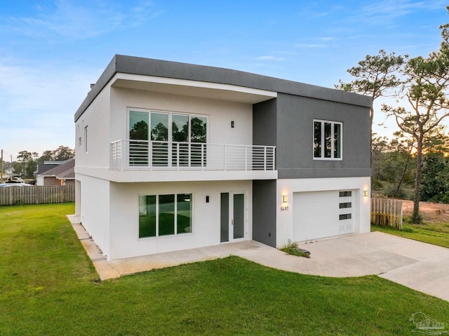 back of property featuring a yard, a balcony, and a garage