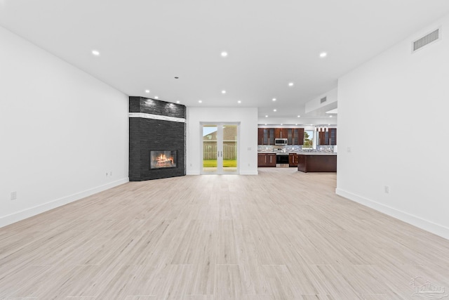 unfurnished living room featuring a fireplace and light hardwood / wood-style floors