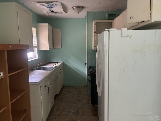 kitchen featuring a sink, light countertops, white cabinetry, visible vents, and freestanding refrigerator