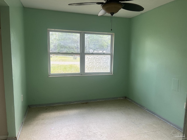 spare room with light floors, a wealth of natural light, a ceiling fan, and baseboards