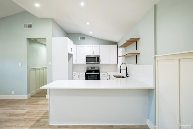 kitchen with sink, stainless steel appliances, light hardwood / wood-style flooring, kitchen peninsula, and vaulted ceiling