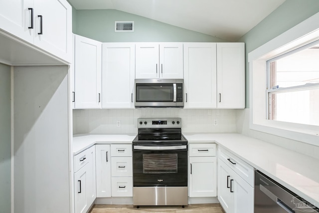 kitchen featuring white cabinetry, stainless steel appliances, and vaulted ceiling