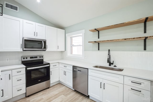 kitchen with white cabinets, lofted ceiling, sink, and appliances with stainless steel finishes