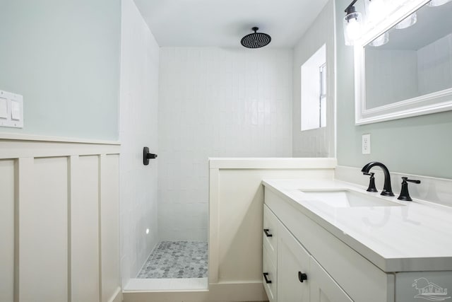 bathroom with a tile shower and vanity