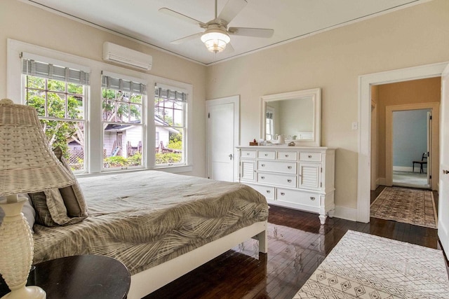 bedroom with a wall mounted air conditioner, crown molding, baseboards, dark wood finished floors, and a ceiling fan