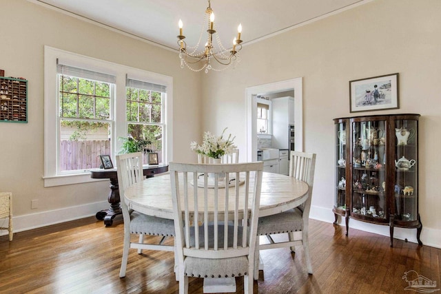dining space with baseboards, wood finished floors, an inviting chandelier, and crown molding