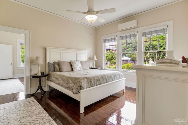 bedroom with wood finished floors, ornamental molding, ceiling fan, baseboards, and a wall unit AC