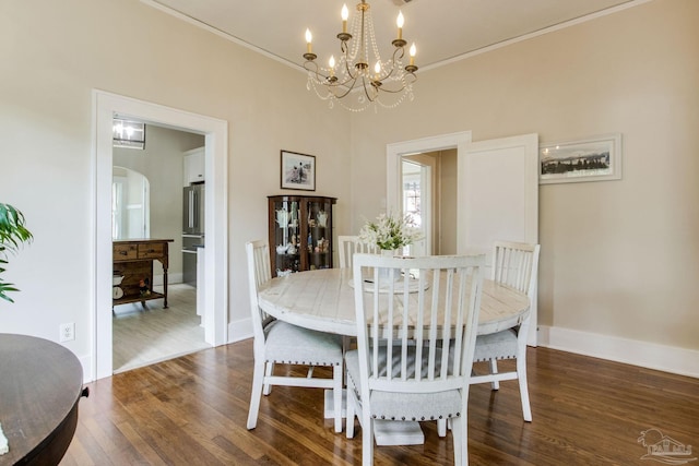 dining area with baseboards, wood finished floors, an inviting chandelier, and arched walkways