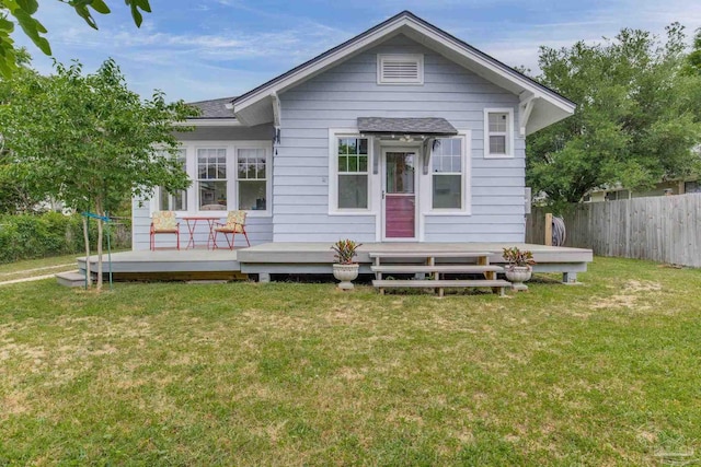 rear view of property featuring a deck, fence, a shingled roof, and a yard