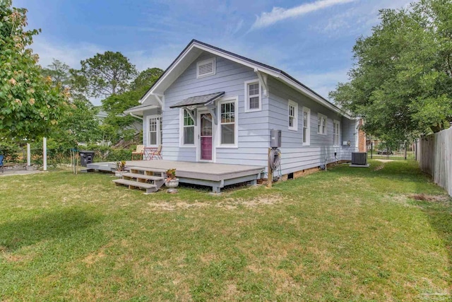 rear view of property with fence, a deck, central AC unit, and a lawn