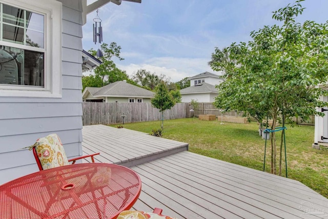 deck featuring outdoor dining area, a yard, and a fenced backyard