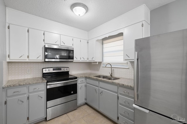 kitchen featuring tasteful backsplash, a textured ceiling, stainless steel appliances, and a sink