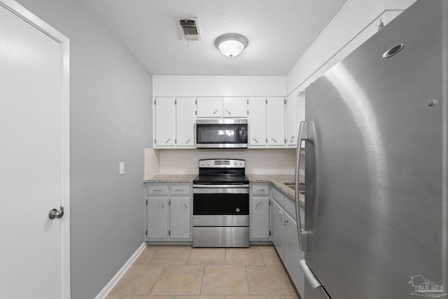 kitchen featuring light tile patterned floors, stainless steel appliances, tasteful backsplash, visible vents, and white cabinetry