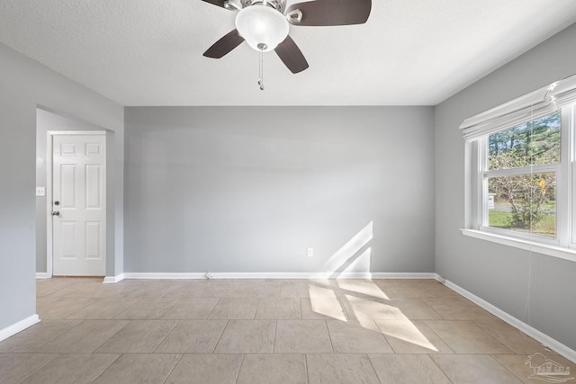 unfurnished room featuring a textured ceiling, baseboards, a ceiling fan, and light tile patterned flooring