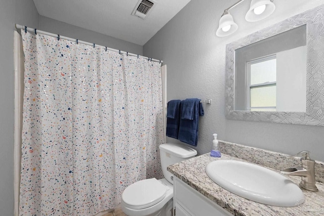 bathroom with a textured wall, toilet, vanity, visible vents, and a shower with curtain