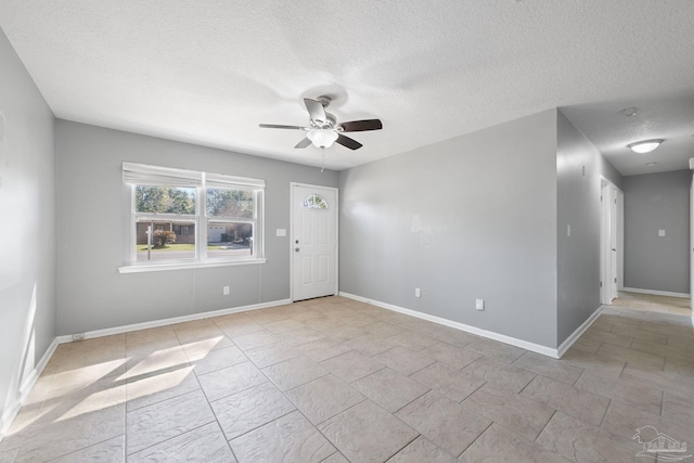 empty room with ceiling fan, a textured ceiling, and baseboards