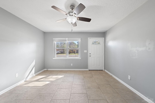 entryway with ceiling fan, a textured ceiling, and baseboards