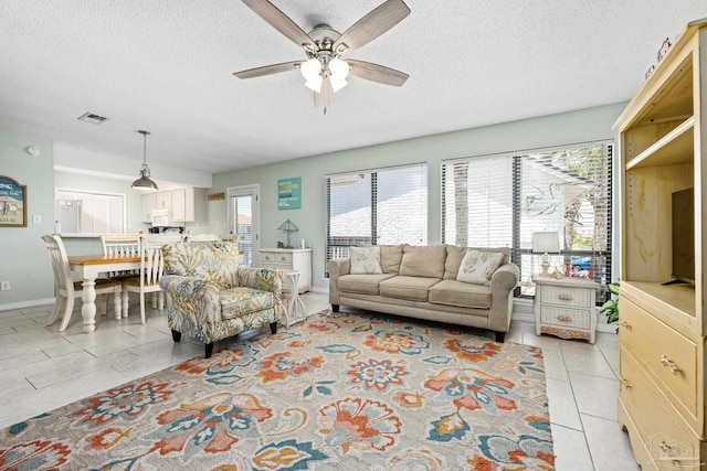 8425 Gulf Blvd Unit 213, Navarre Beach, FL 32566 - living area with a ceiling fan, a textured ceiling, healthy amount of natural light, light tile patterned floors, and baseboards