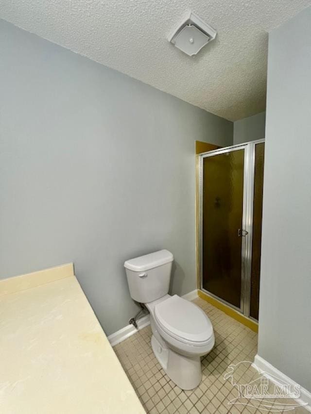 bathroom with a textured ceiling, toilet, and walk in shower