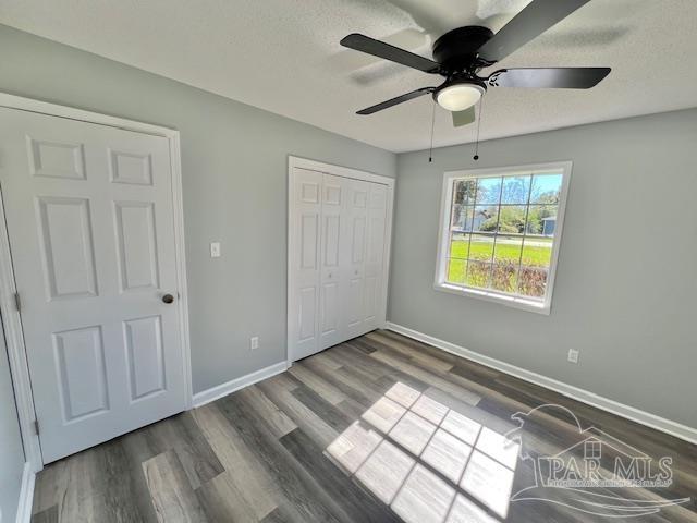 unfurnished bedroom featuring ceiling fan, dark hardwood / wood-style flooring, a textured ceiling, and a closet