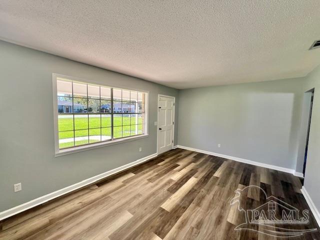 spare room featuring a textured ceiling and dark wood-type flooring