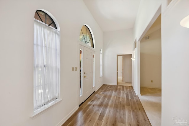 entryway with a towering ceiling and light hardwood / wood-style floors