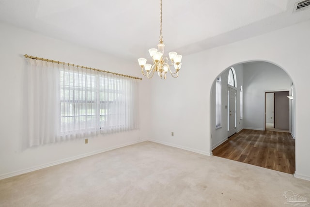 carpeted empty room featuring a notable chandelier