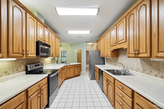 kitchen with sink, a textured ceiling, decorative backsplash, light tile patterned flooring, and appliances with stainless steel finishes