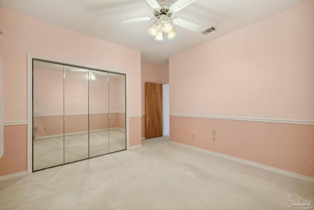 unfurnished bedroom with a closet, light colored carpet, and ceiling fan