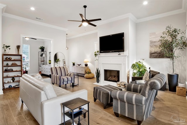 living room with crown molding, ceiling fan, and light hardwood / wood-style flooring