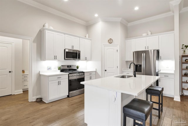 kitchen with appliances with stainless steel finishes, sink, a center island with sink, and white cabinets