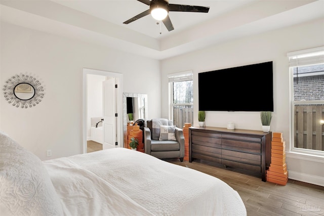 bedroom with connected bathroom, hardwood / wood-style floors, ceiling fan, and a tray ceiling