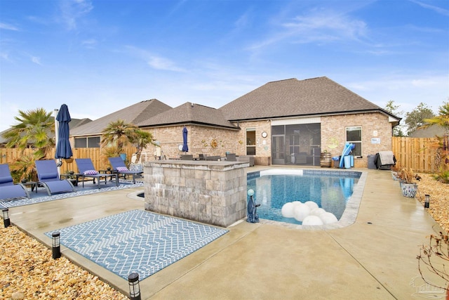 view of pool with a bar, a sunroom, and a patio