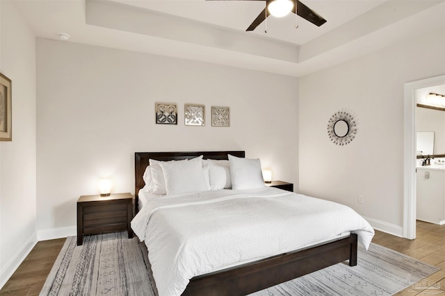 bedroom with a raised ceiling, hardwood / wood-style floors, and ceiling fan