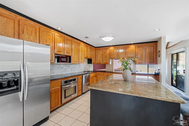 kitchen featuring stainless steel appliances, sink, a center island, light tile patterned flooring, and light stone counters