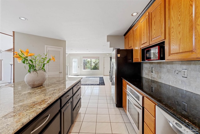 kitchen with light stone countertops, tasteful backsplash, appliances with stainless steel finishes, and light tile patterned floors