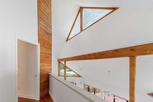 hallway featuring wood-type flooring, a high ceiling, and wooden walls