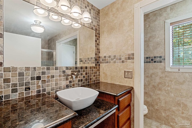 bathroom with backsplash, tile walls, toilet, a shower with shower door, and vanity