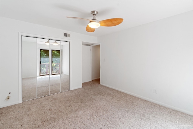 unfurnished bedroom featuring light colored carpet, a closet, and ceiling fan