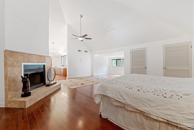 bedroom with hardwood / wood-style floors, multiple closets, high vaulted ceiling, and ceiling fan