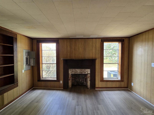 unfurnished living room featuring electric panel, wooden walls, dark hardwood / wood-style flooring, and built in features