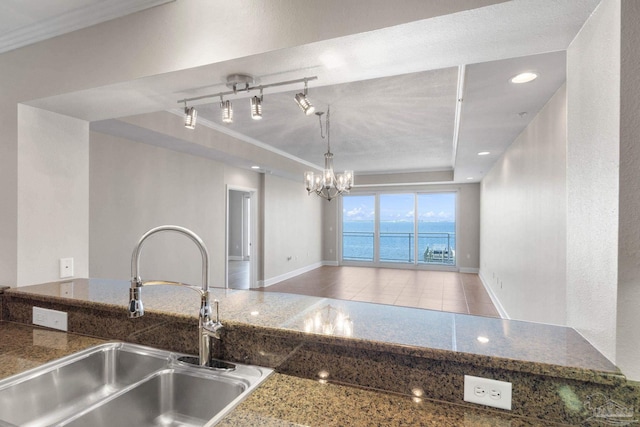 kitchen with a water view, sink, crown molding, light tile patterned floors, and a notable chandelier