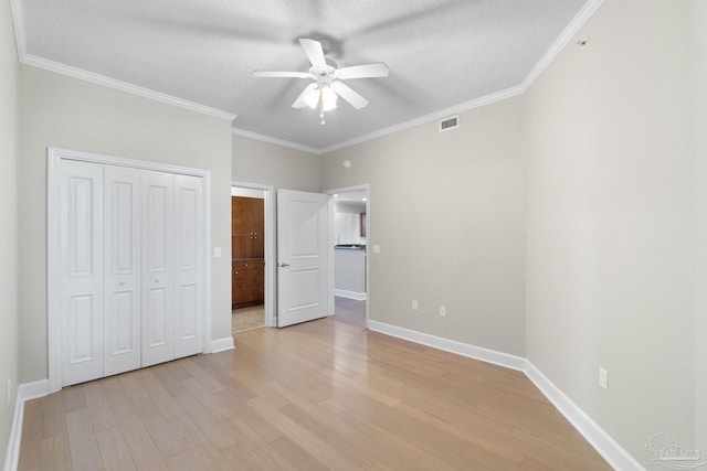 unfurnished bedroom with a textured ceiling, ceiling fan, light wood-type flooring, and ornamental molding