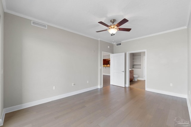 unfurnished bedroom featuring ceiling fan, wood-type flooring, a textured ceiling, a walk in closet, and ornamental molding