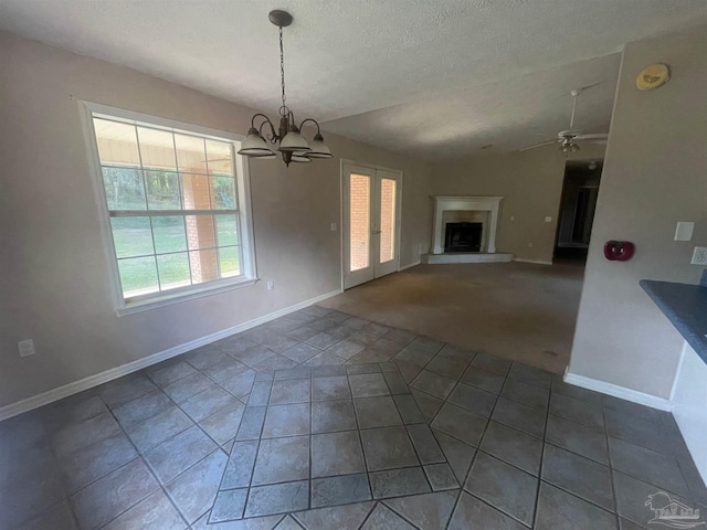 unfurnished living room with dark carpet, vaulted ceiling, a textured ceiling, and ceiling fan with notable chandelier