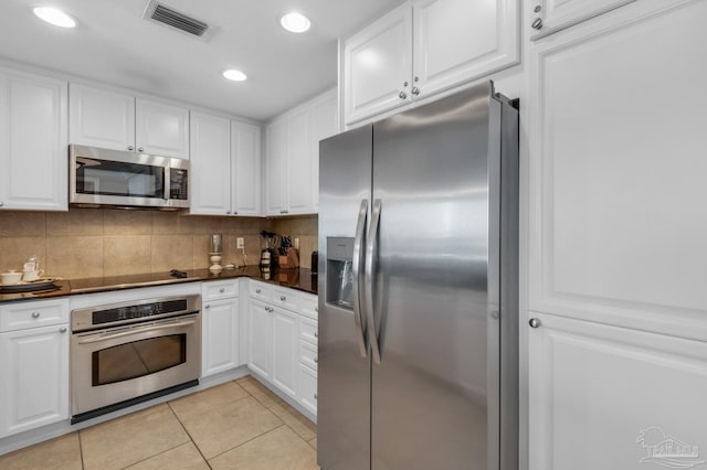 kitchen with stainless steel appliances, white cabinetry, and light tile patterned flooring